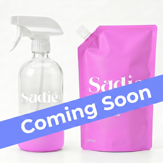 Clear spray bottle and pink refill pouch with 'Sadie' branding on a white background, featuring 'Coming Soon' text.